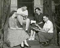 Four adults seated on front steps of Main Library
