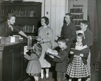 Family checking out books at the Circulation desk, Main Library