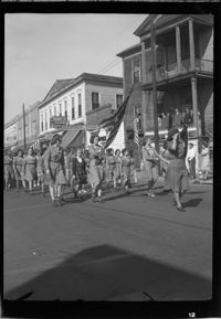 Girl Scouts marching in the Armistice Day parade in front of the John Mark Verdier House