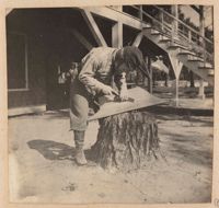 Man carving model boat keel on tree stump