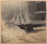 Model boat with sails ashore in front of Main house
