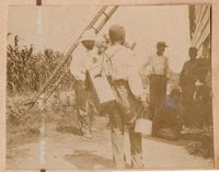 Conrad Donner with group of workers near corn field and barn