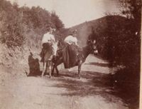 Two women on mules with hills in background
