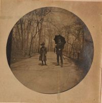 Child and man with umbrella in wooded area.