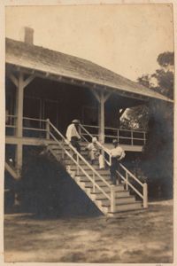 Three men lounging on the steps of the main house at Halls Island