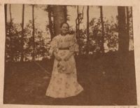 Unidentified young woman posing by tree